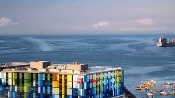 Un edificio moderno con fachada colorida, cerca de un cuerpo de agua con barcos.
