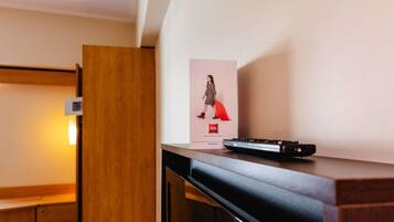 Una habitación de hotel con un armario de madera, un control remoto sobre una encimera y un cartel en la pared.