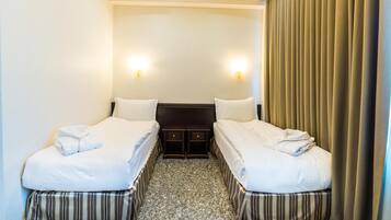 A hotel room with two beds, a small table, and a headboard.