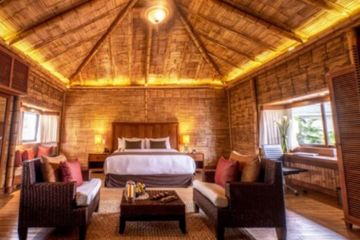 A spacious room with a large bed, two sofas, a coffee table, and a wooden ceiling.