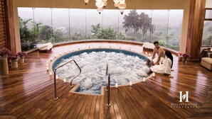 A hot tub in a spacious room with large windows, wooden flooring, and hanging light fixtures. - Hillary Nature Resort Spa (Arenillas)