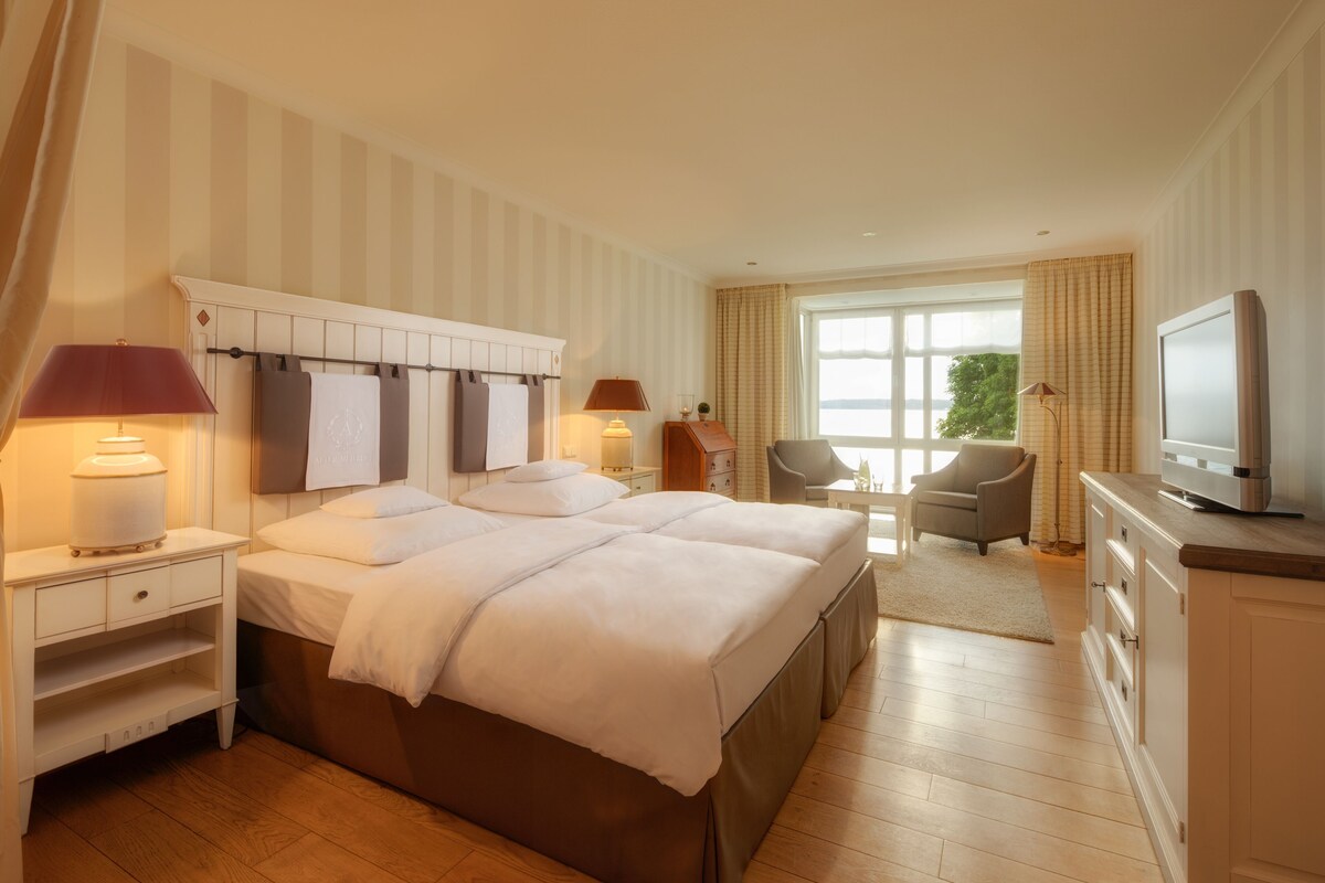 A hotel room with a large bed, a TV, a desk, and a chair.