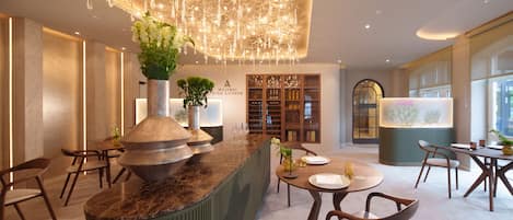 A modern hotel lobby with a marble reception desk, seating area, and a wine display.
