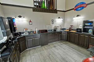 Cozinha equipada com máquina de café, torradeira e frigorífico.