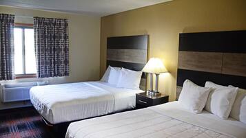 Habitación de hotel con dos camas, una mesita de noche con lámpara, una ventana con cortinas y un aire acondicionado instalado en la pared.