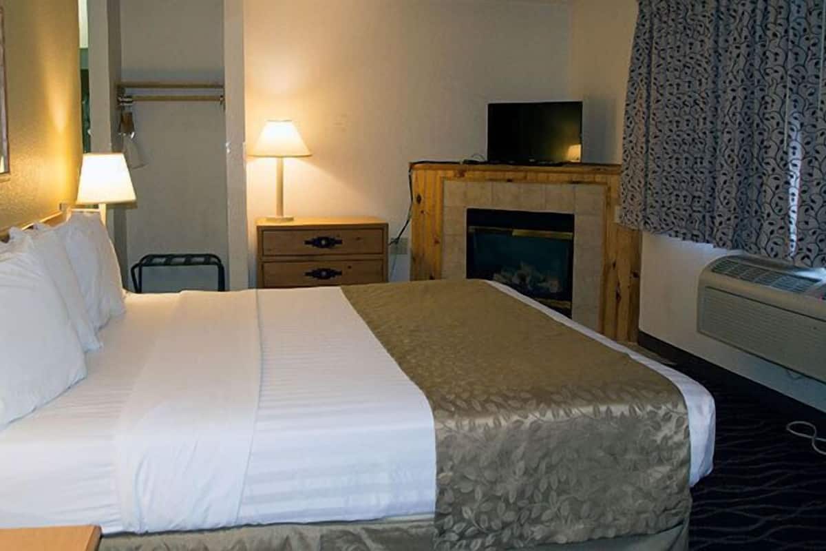 Une chambre d’hôtel équipée d’un lit, de lampes de chevet, d’une télévision, d’une cheminée et d’un téléphone.