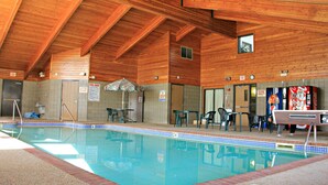 Une piscine intérieure avec des poutres en bois au plafond, un sol carrelé et un distributeur automatique de Coca-Cola.