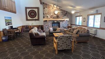 A spacious living area with a stone fireplace, multiple seating options, and a patterned carpet.
