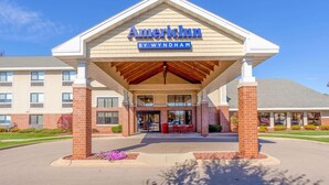 A hotel entrance with a covered area, a sign reading "AmericInn by Wyndham", and a parking lot. - AmericInn by Wyndham Madison South (Madison)