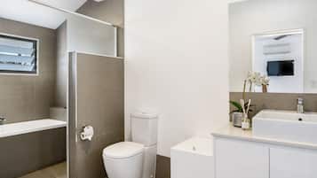 Un baño moderno con ducha, inodoro, lavabo y espejo.