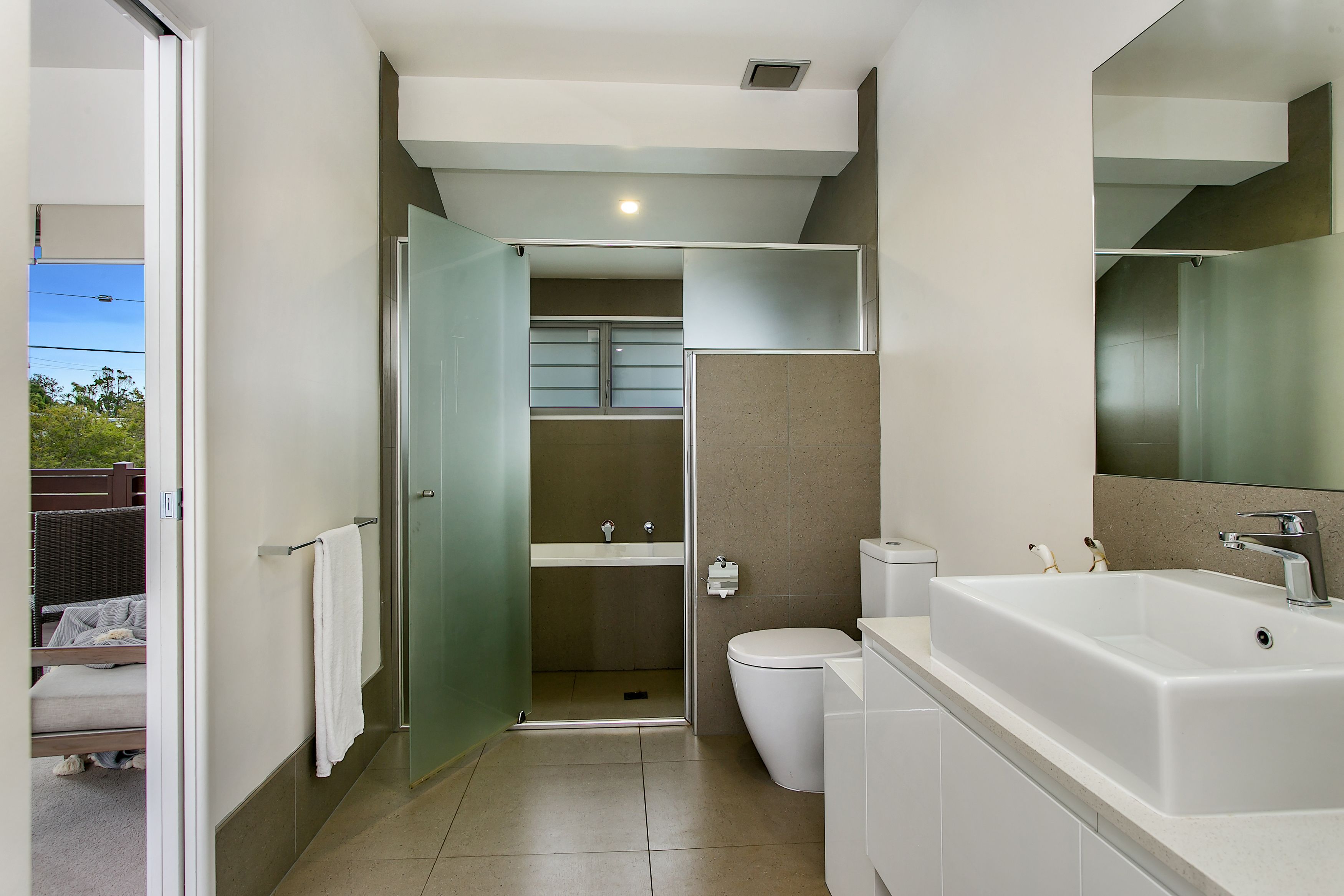A modern bathroom with a large white bathtub, a toilet, and a glass-enclosed shower area.