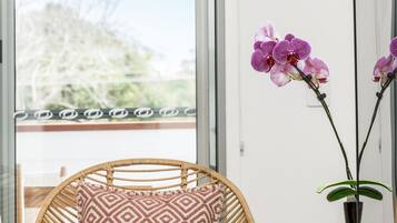 A room with a wicker chair, a wooden desk, and a potted orchid.