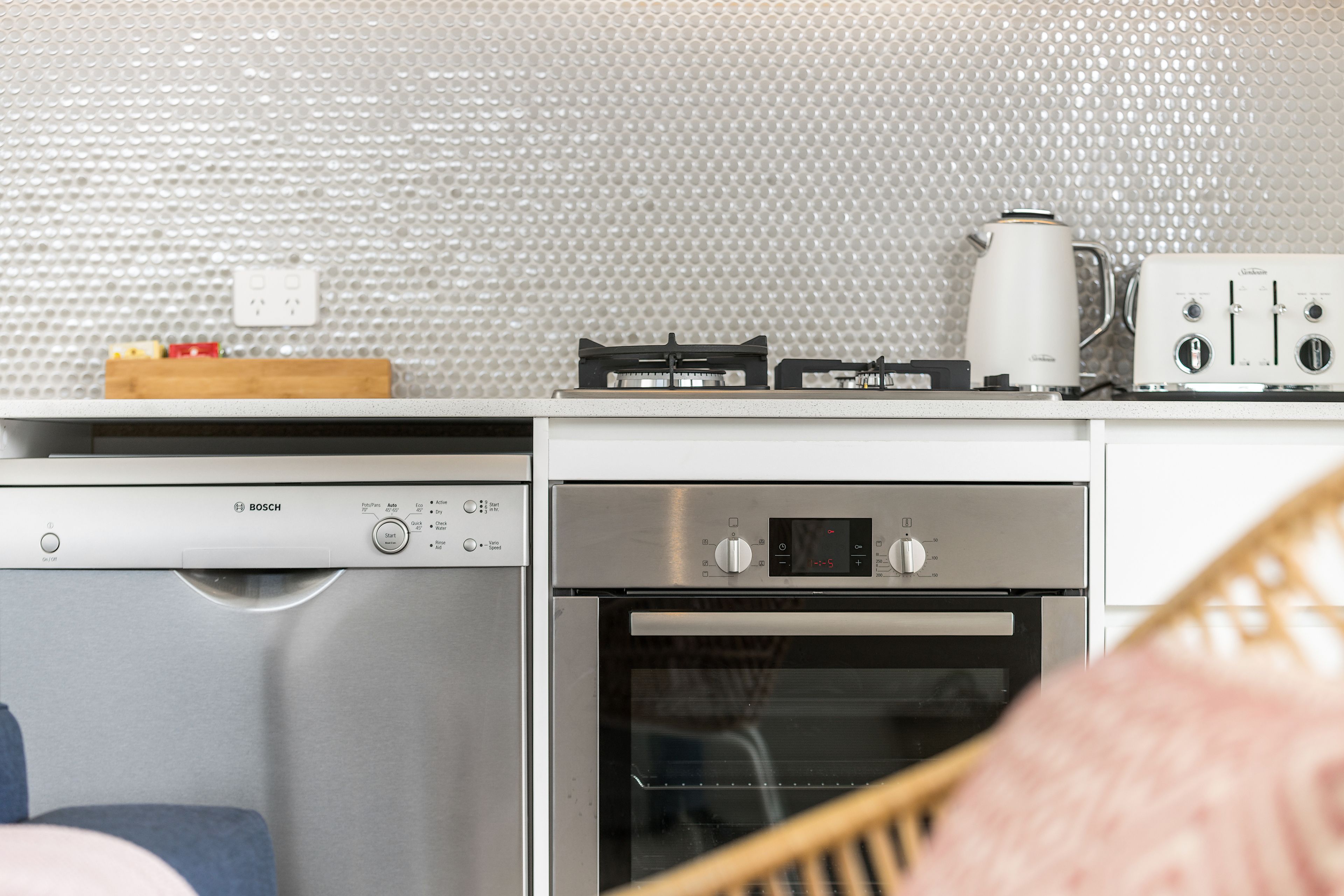 Een functionele keuken met een Bosch vaatwasser, een inbouwoven, een koffiezetapparaat en een broodrooster.