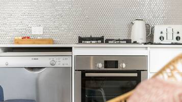 Een functionele keuken met een Bosch vaatwasser, een inbouwoven, een koffiezetapparaat en een broodrooster.
