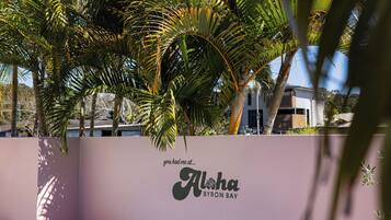 A swimming pool with a pink wall and palm trees.