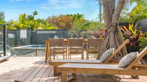 Une terrasse en bois avec une piscine, des chaises longues et une table à manger.
