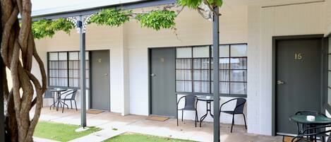 A building with numbered doors, outdoor seating, and a tree.