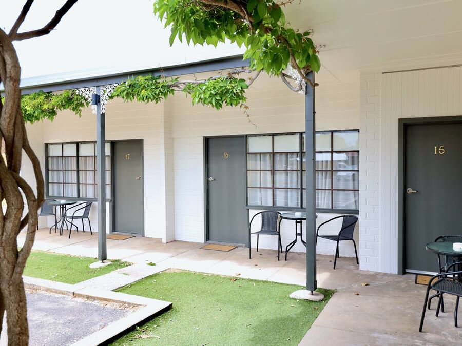 A building with numbered doors, outdoor seating, and a tree.