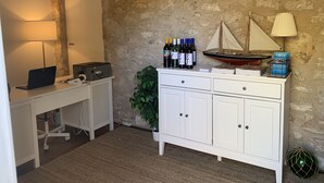 A room with a white desk, a computer, a lamp, a potted plant, a cabinet with wine bottles, and a model ship. - Guichen Bay Motel (Robe)