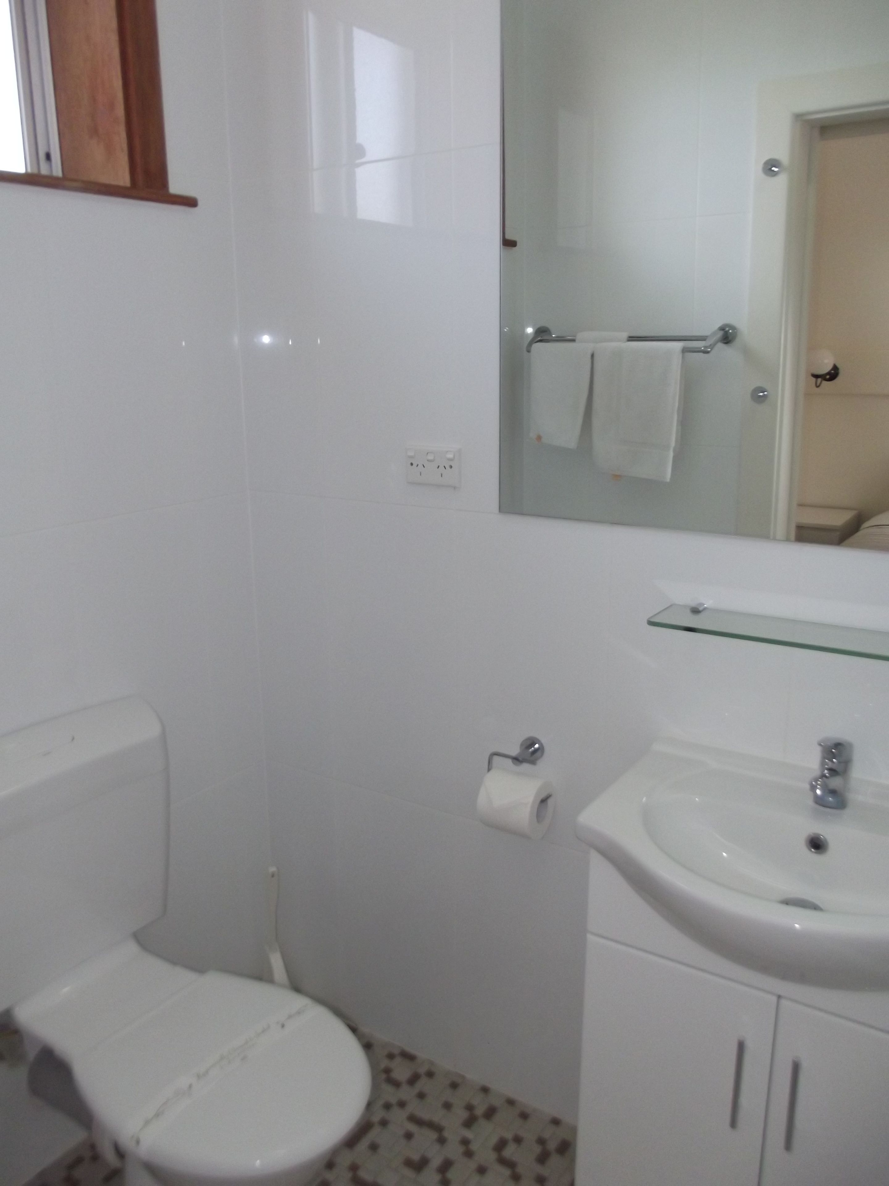 A small bathroom with a toilet, sink, and mirror.