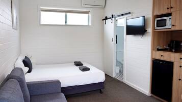 Ein gemütlicher Raum mit Bett, einer Schlafcouch, Fernseher, Mikrowelle und Kühlschrank.
