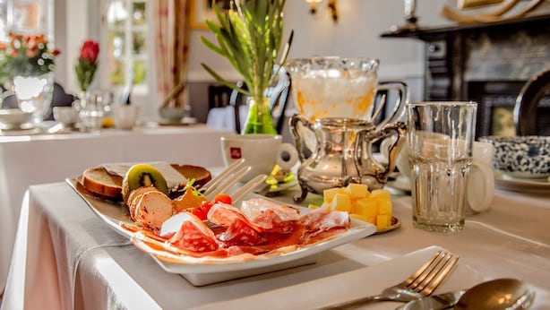 A dining table with a plate of food, cutlery, and a pitcher of water.