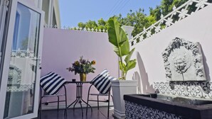 An outdoor seating area with a table and chairs, a potted plant, and a decorative wall.