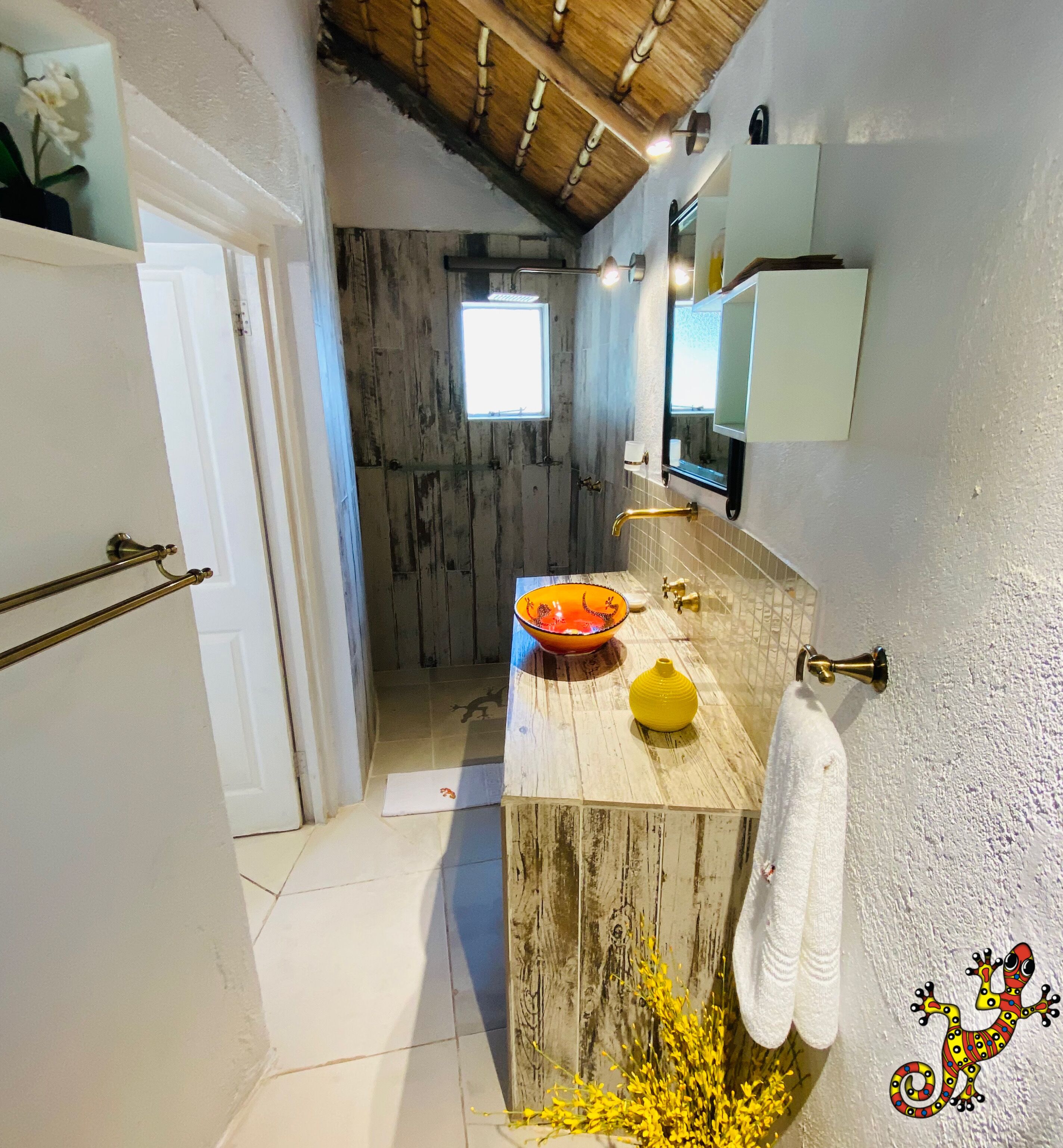 A bathroom with a wooden vanity, a yellow vase, a white towel, and a mirror.