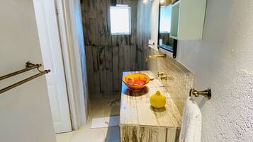 A bathroom with a wooden vanity, a yellow vase, a white towel, and a mirror.
