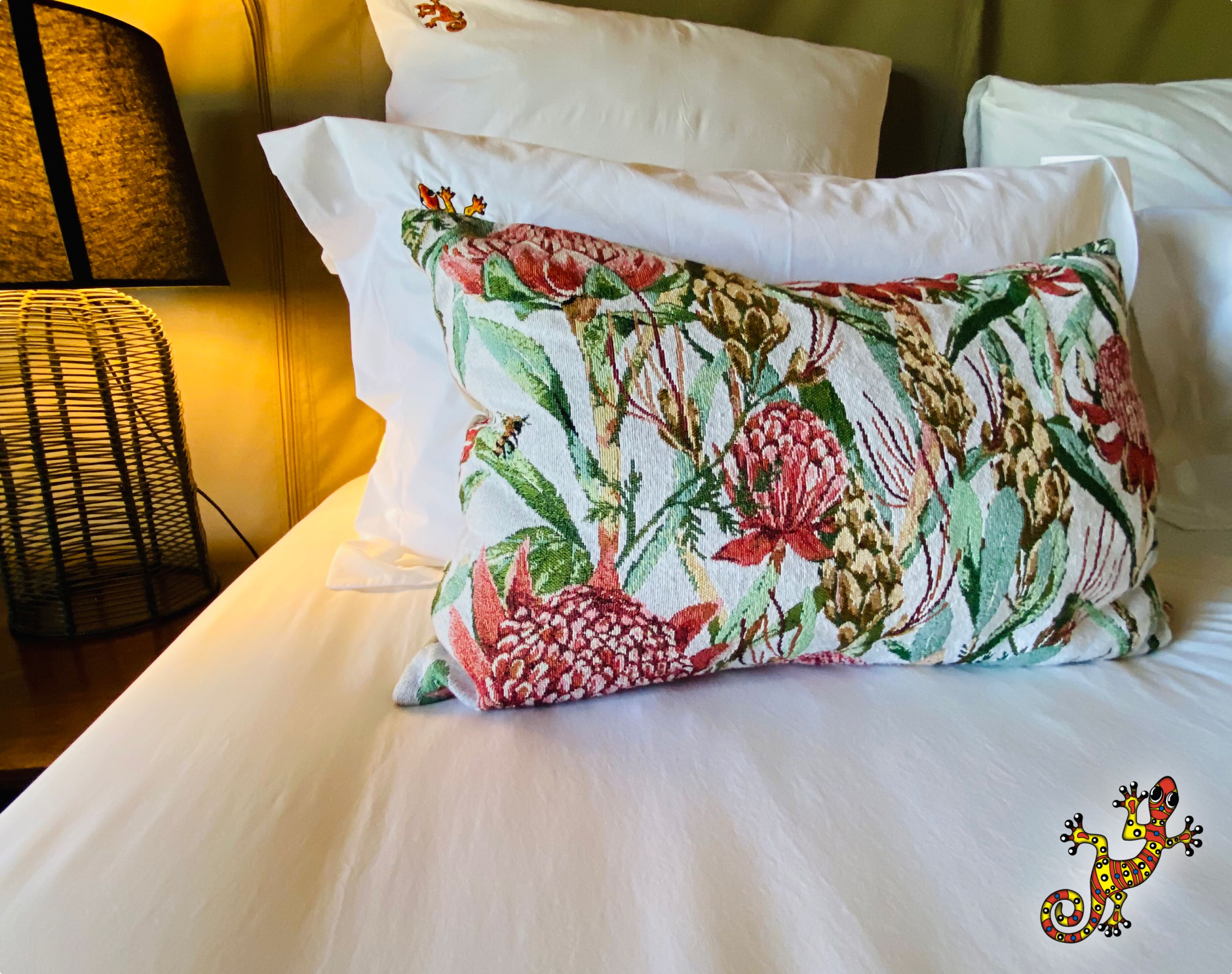 A bed with white linens and a floral-patterned pillow.