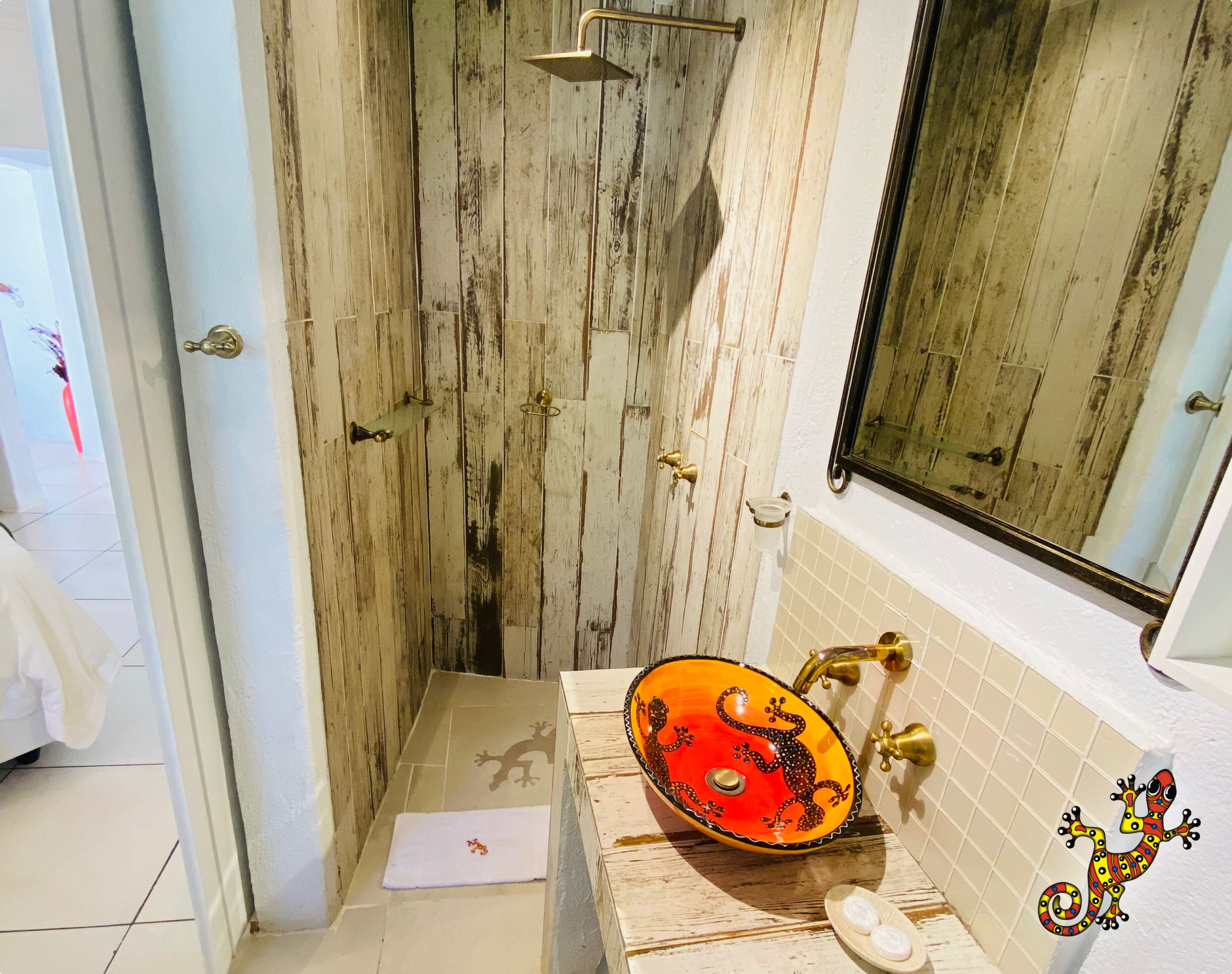 Ein Badezimmer mit Holztür, Waschbecken mit dekorativer Schale und Spiegel.
