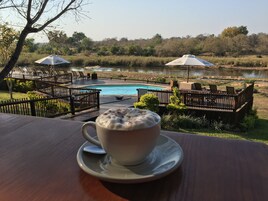 Una taza de café sobre una mesa, con vistas a una piscina y el paisaje circundante.