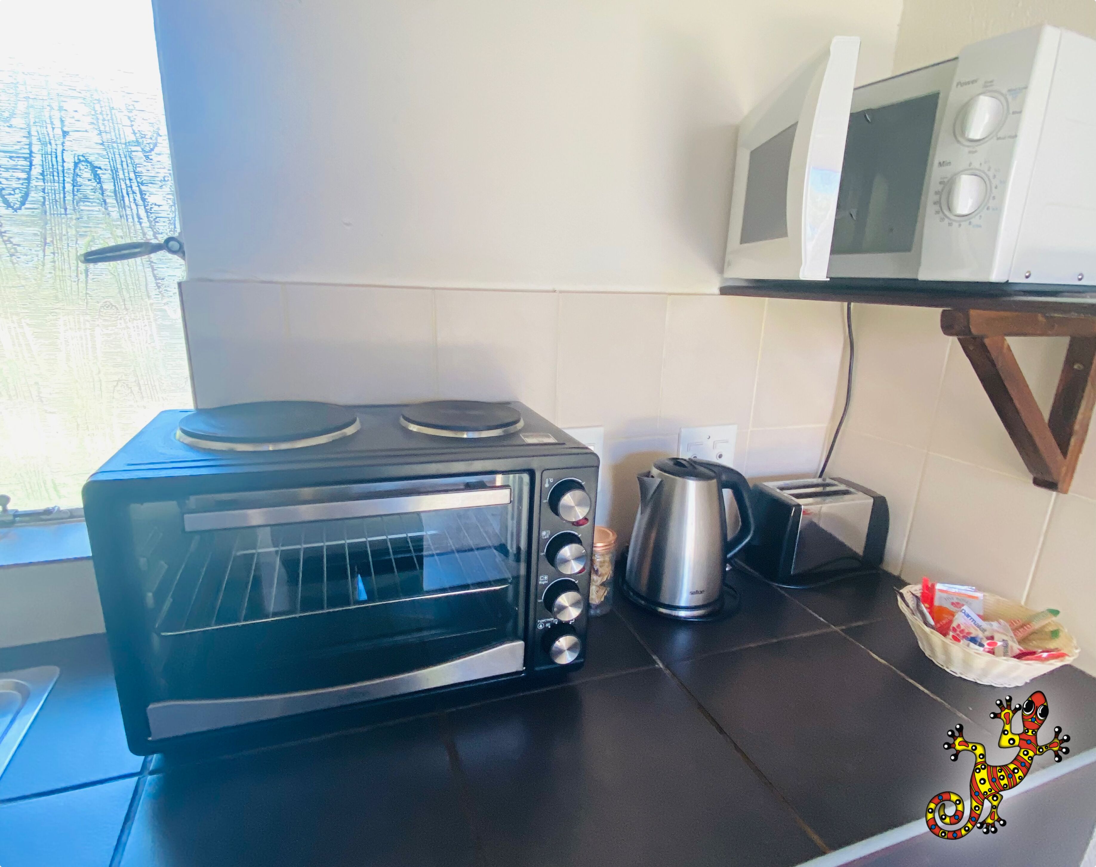 Una cocina con horno tostador negro, hervidor, microondas y tostadora sobre la encimera.