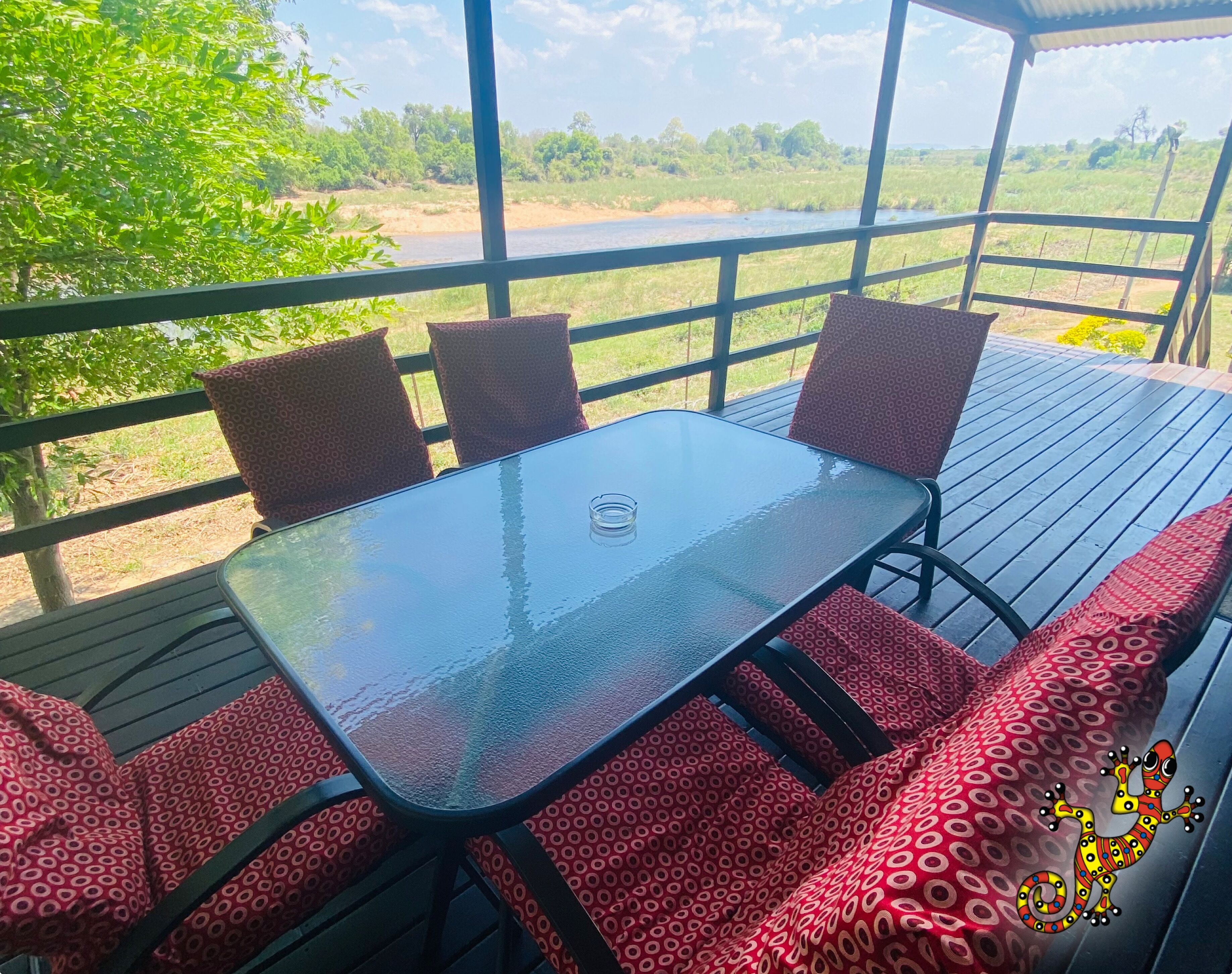 Un espace extérieur abrité, avec une table en verre et des coussins à motifs.