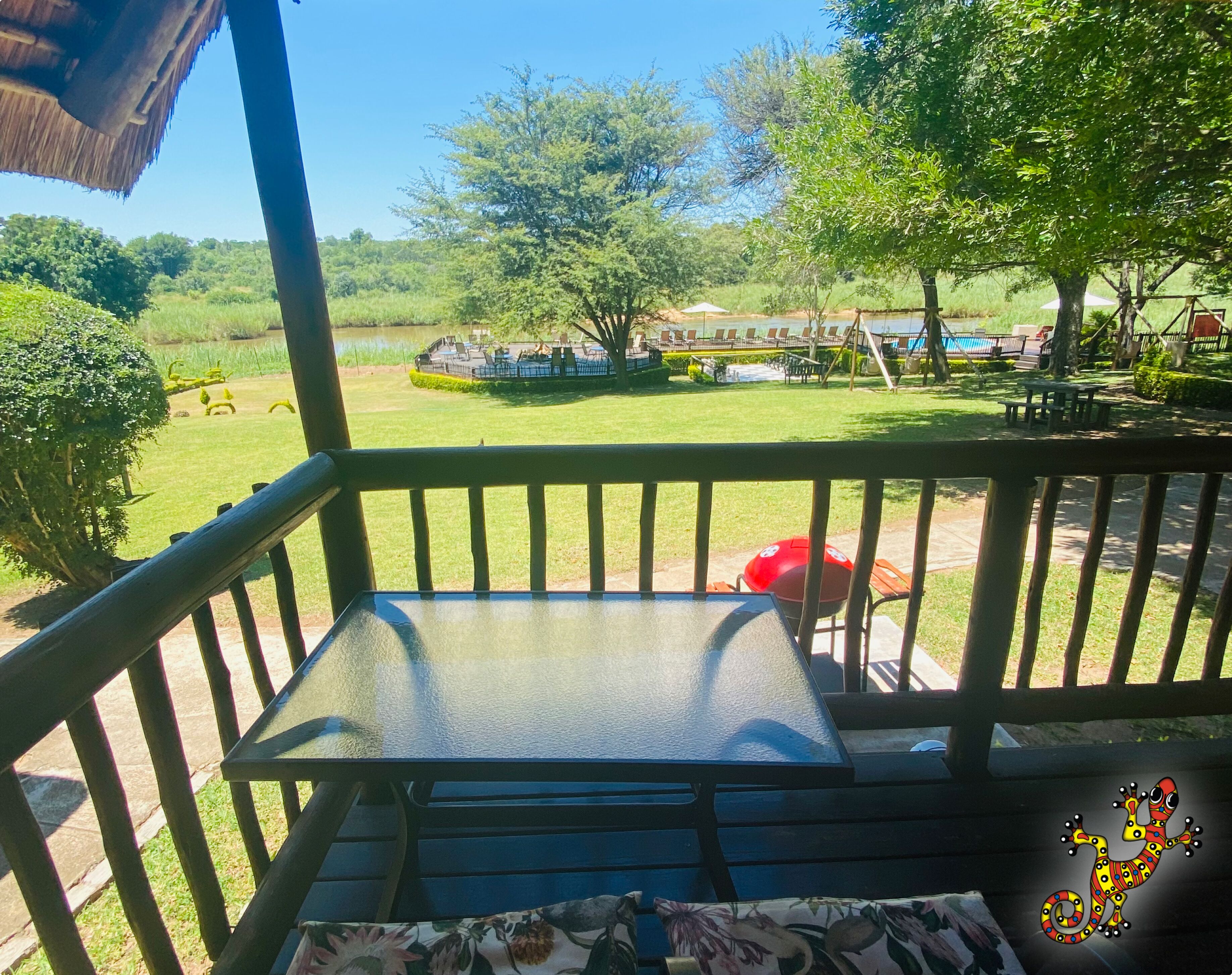 Vista desde un balcón sobre un jardín cuidado con piscina, mobiliario exterior y un pabellón.