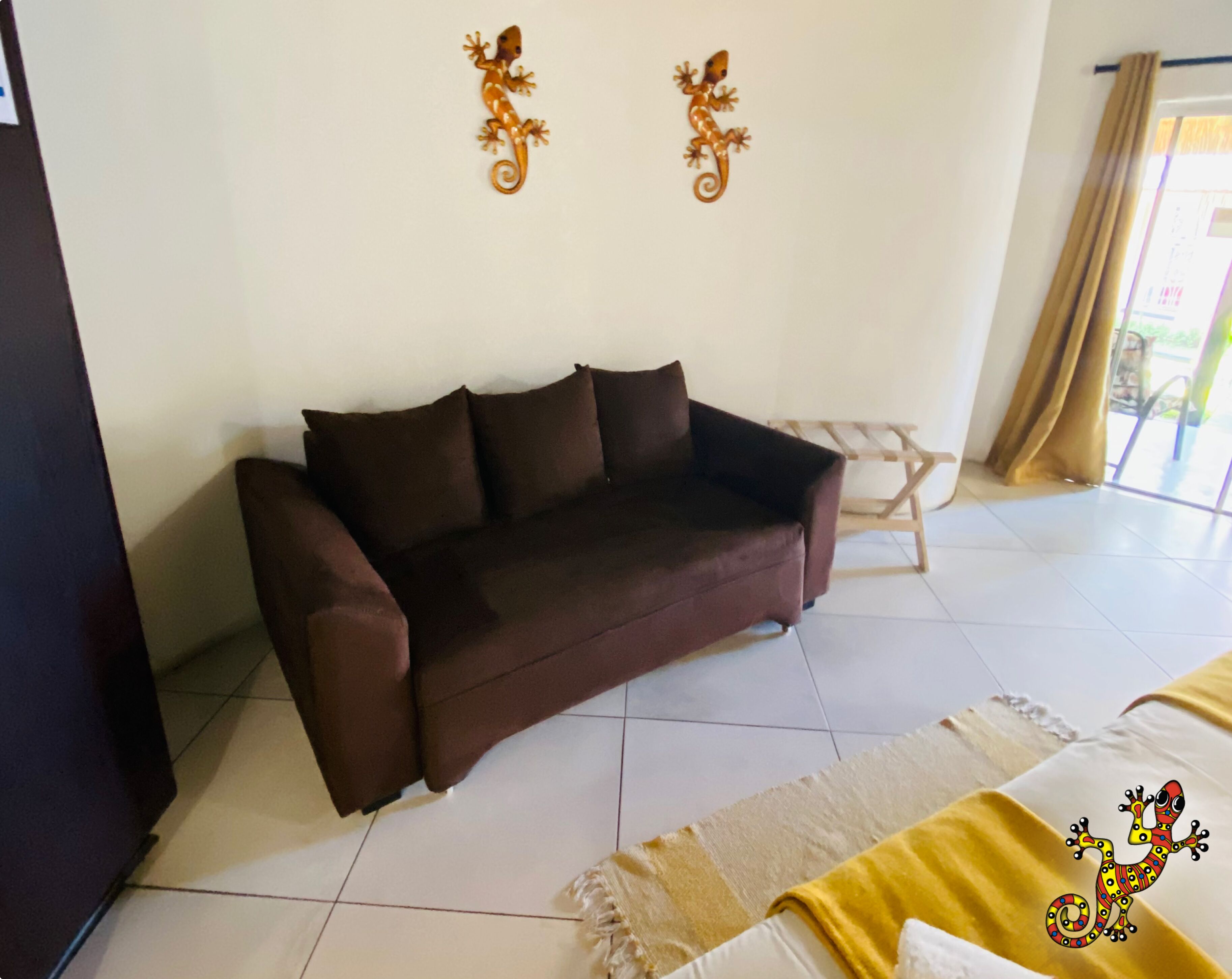 A room with a brown sofa, a small wooden stool, and a patterned rug.