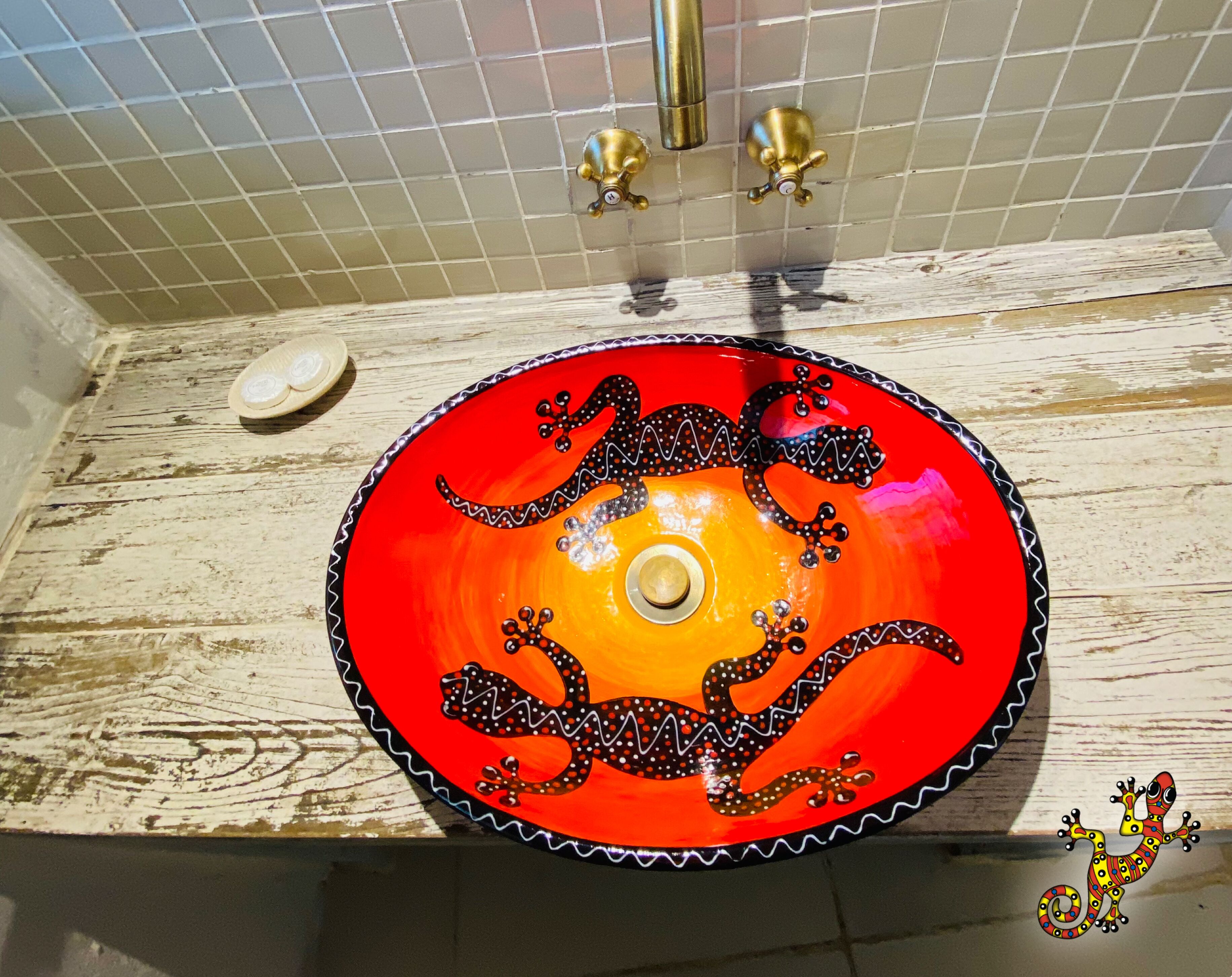 A bathroom with a red and orange sink, a white tiled wall, and a wooden countertop.