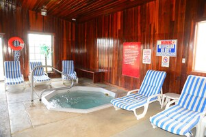 A wooden cabin with a hot tub, striped lounge chairs, and a lifebuoy.