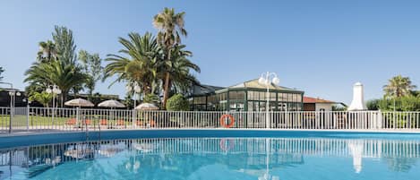 Una piscina al aire libre de temporada, sombrillas, tumbonas