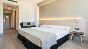 A modern hotel room with a large bed, a bedside table, and a nightstand. - Hotel ILUNION Las Lomas (Merida)