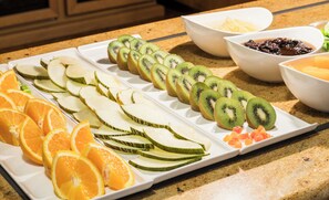 A fruit platter with sliced oranges, kiwi, and melon on a white plate.