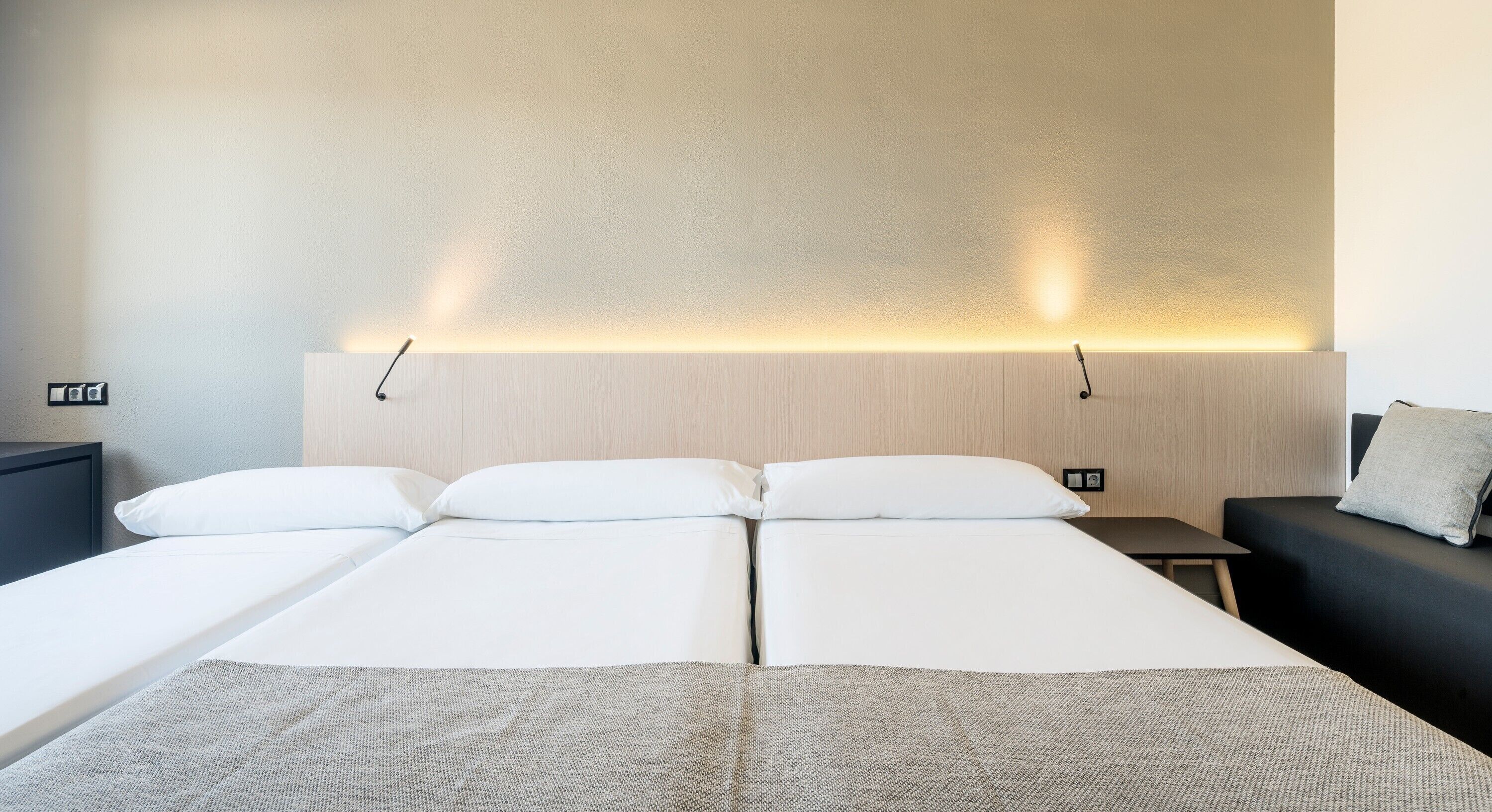 Habitació d'hotel amb un llit gran, una taula de nit i un sofà.