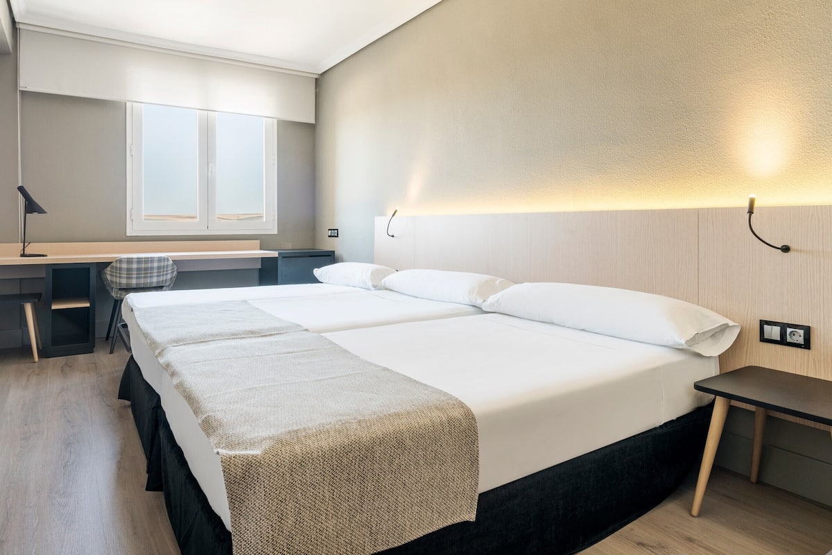 Ein Hotelzimmer mit einem großen Bett, einem Schreibtisch und einem Sessel.