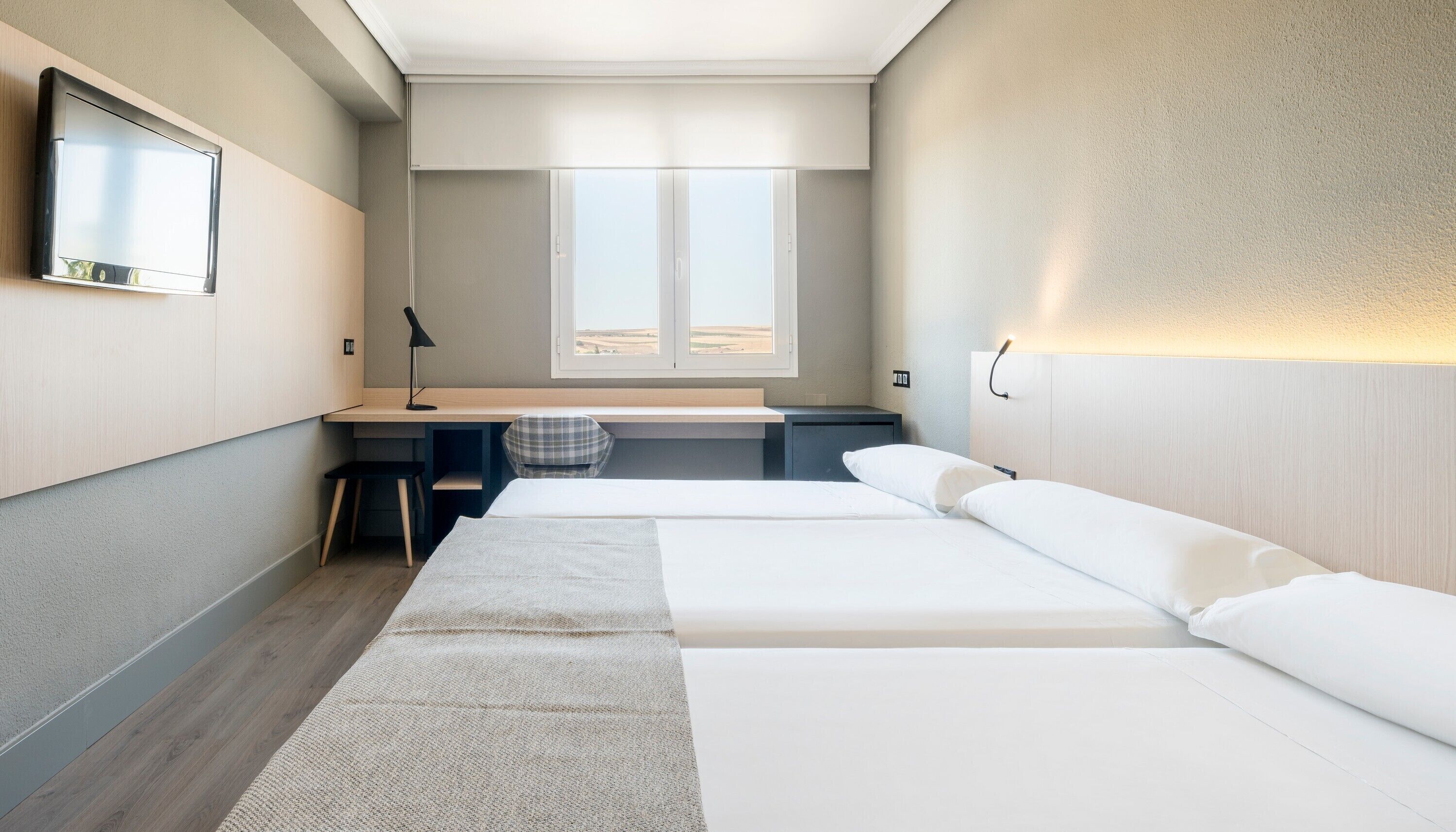 Un hotel modern amb llit, escriptori i cadira.