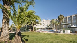 A hotel courtyard with palm trees, a pool area, and a building with a "HOTEL" sign. - Hotel ILUNION Las Lomas (Merida)