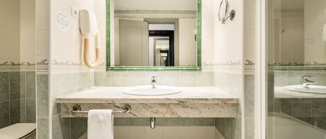 A bathroom with a marble sink, a mirror, a towel rack, and a shower area.