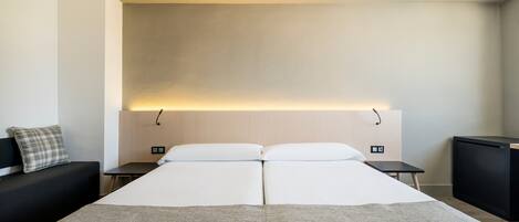A hotel room with a large bed, two bedside tables, a small TV, and a decorative wall panel.