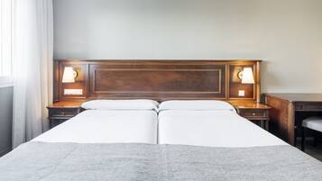 A double bed with a wooden headboard, two bedside tables with lamps, and a plain wall.