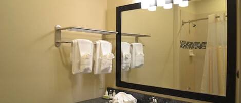 A bathroom with a large mirror, a sink, and a towel rack with multiple towels.