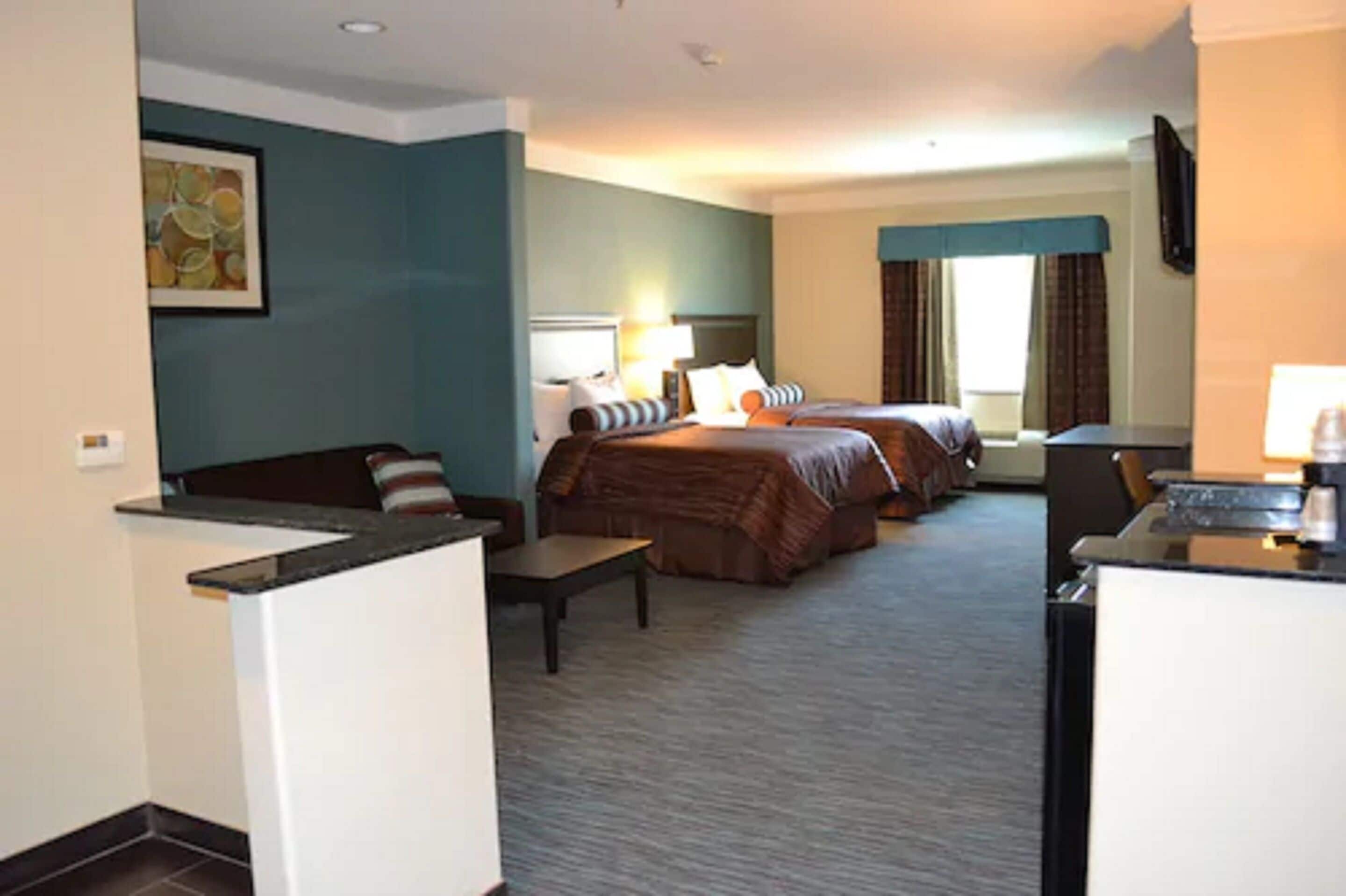 Een hotelkamer met twee bedden, een bureau, een stoel, een klein tafeltje en een televisie.